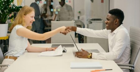 Free Business professionals completing a successful deal with a handshake in a modern office setting. Stock Photo