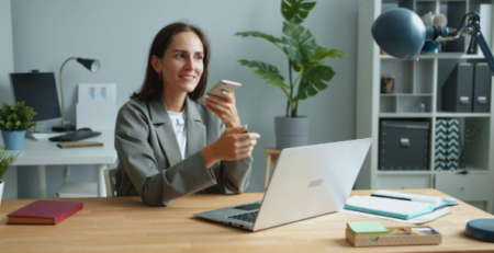 lady holding phone while working on a laptop